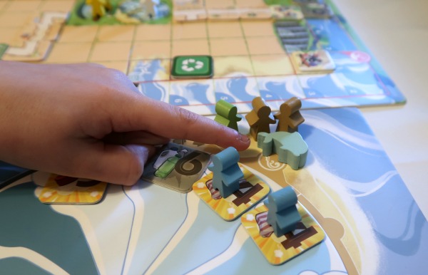 Dolphin game piece and meeples on the Ocean Crisis game board.