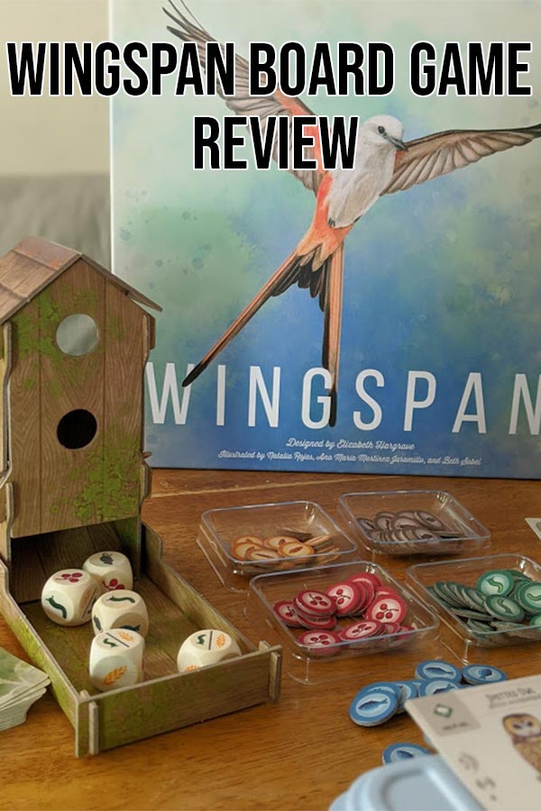 Game components set out on table in front of Wingspan game box with text overlay stating Wingspan Board Game Review.