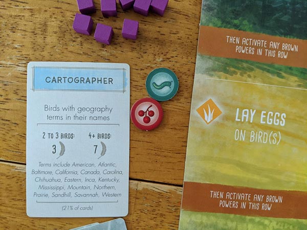 Cartographer bonus objective card for Wingspan on table next to food tokens and player mat.